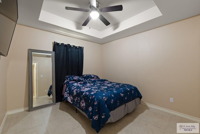 bedroom with a raised ceiling, light tile patterned floors, and ceiling fan