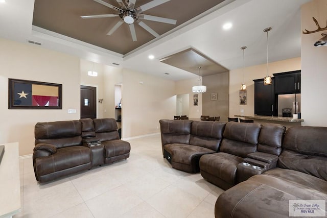 cinema room with light tile patterned floors, a raised ceiling, and ceiling fan