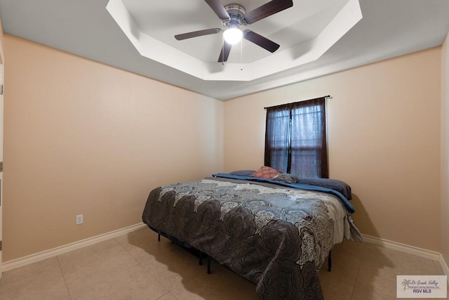 bedroom with a raised ceiling, light tile patterned flooring, and ceiling fan