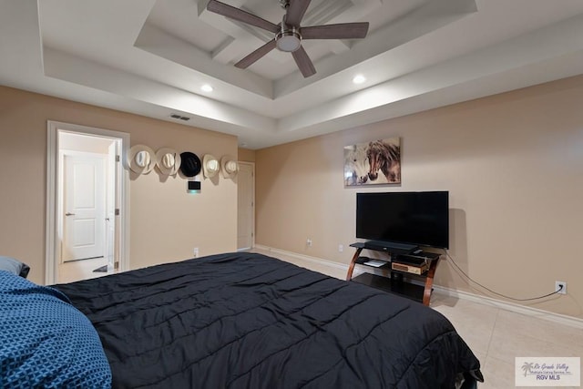 bedroom with light tile patterned floors, ceiling fan, and a tray ceiling