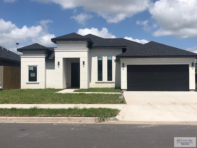 prairie-style home featuring a garage and a front lawn