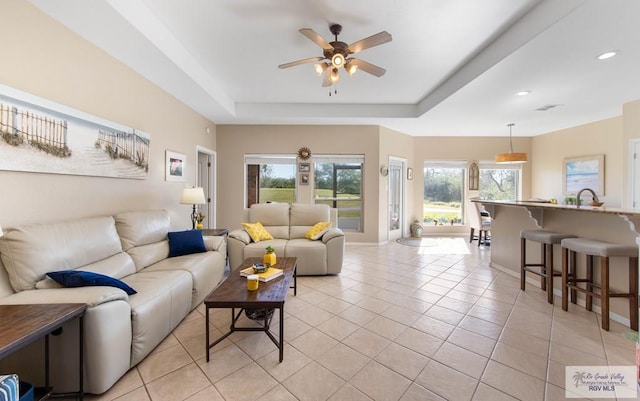 living area with recessed lighting, a raised ceiling, ceiling fan, and light tile patterned floors