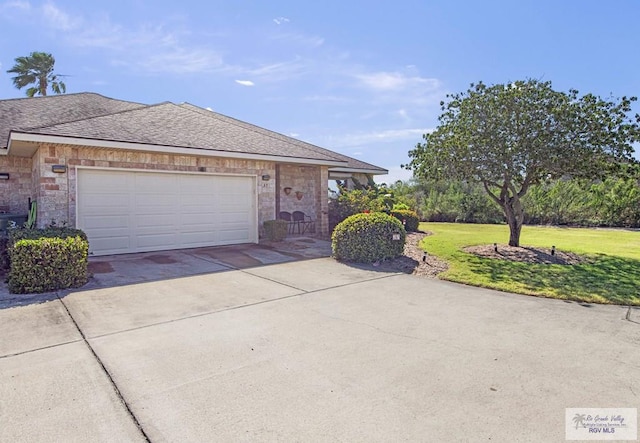 view of side of home featuring an attached garage, a shingled roof, a yard, concrete driveway, and stone siding