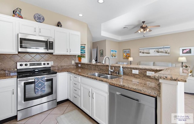 kitchen featuring appliances with stainless steel finishes, light tile patterned flooring, a sink, and tasteful backsplash