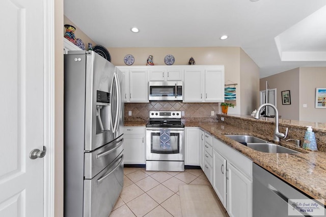 kitchen with light tile patterned floors, decorative backsplash, appliances with stainless steel finishes, white cabinets, and a sink