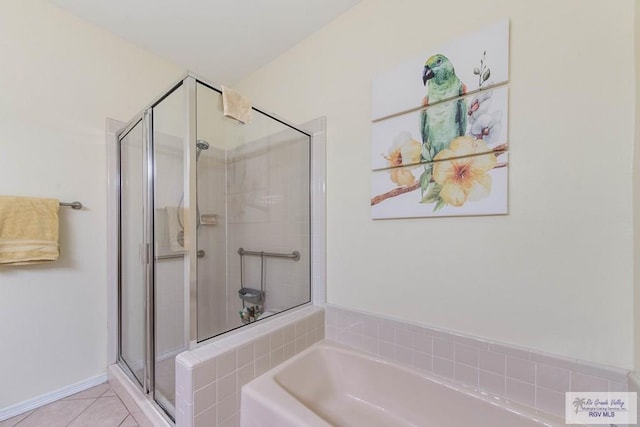 bathroom with a stall shower, a garden tub, baseboards, and tile patterned floors