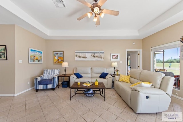 living area with baseboards, visible vents, a tray ceiling, and light tile patterned flooring