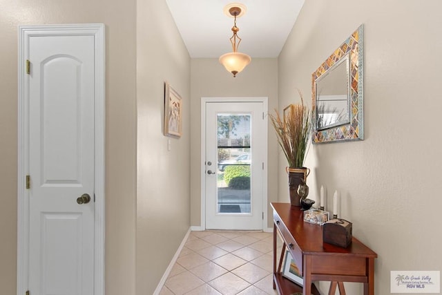 doorway featuring light tile patterned floors and baseboards