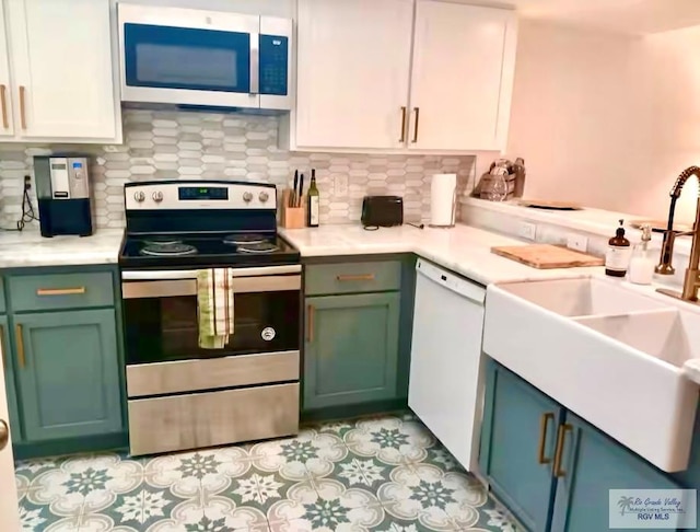 kitchen with appliances with stainless steel finishes, light countertops, a sink, and backsplash