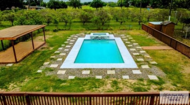 view of swimming pool featuring a lawn and a pool with connected hot tub