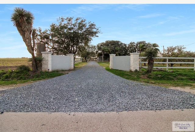 view of street featuring gravel driveway and a gate