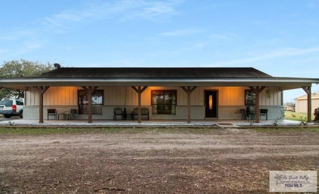 farmhouse featuring an attached carport, board and batten siding, and brick siding