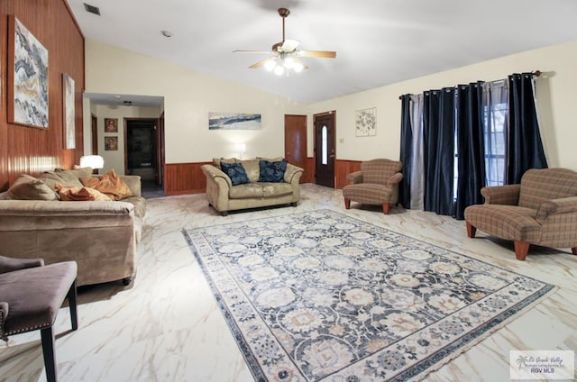 living area featuring visible vents, wooden walls, a wainscoted wall, lofted ceiling, and marble finish floor