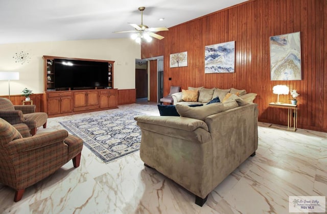 living area featuring marble finish floor, lofted ceiling, wood walls, and ceiling fan