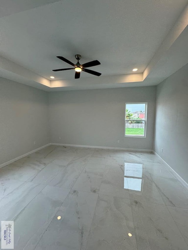 spare room featuring ceiling fan and a tray ceiling