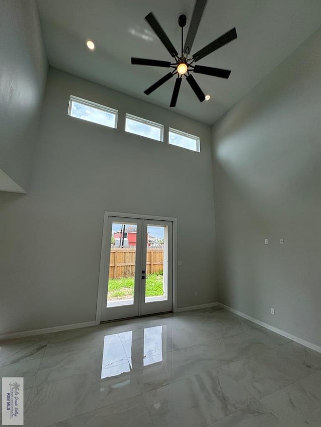 spare room with a wealth of natural light, french doors, ceiling fan, and a high ceiling