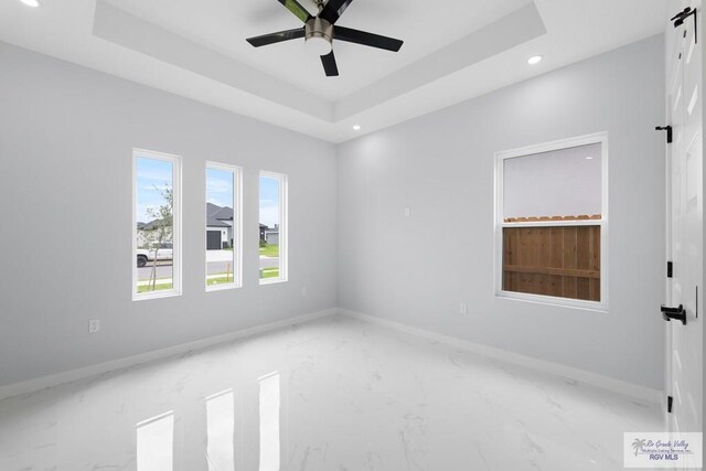 empty room featuring a raised ceiling and ceiling fan