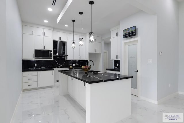 kitchen with white cabinets, hanging light fixtures, decorative backsplash, a kitchen island, and extractor fan