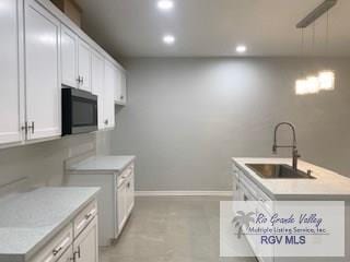 kitchen with pendant lighting, white cabinetry, and sink