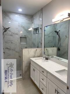 bathroom featuring a tile shower, vanity, and tile walls