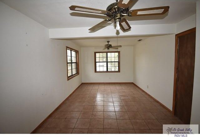 unfurnished room featuring baseboards, a ceiling fan, and tile patterned floors