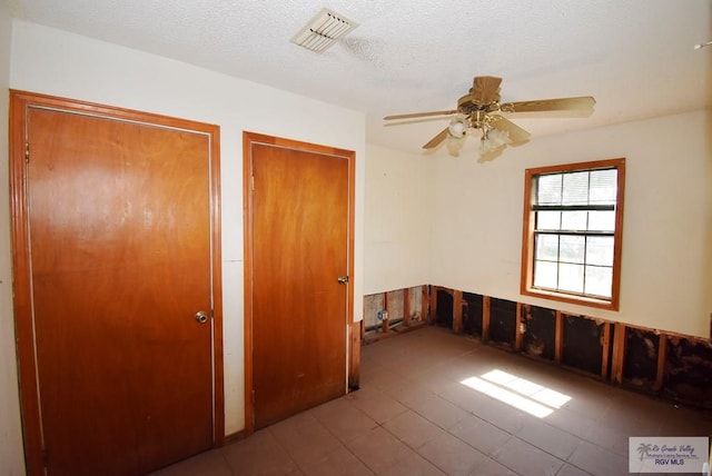 195 W 3rd St, Sebastian, TX 78594 - unfurnished bedroom featuring a textured ceiling, multiple closets, ceiling fan, and tile patterned flooring