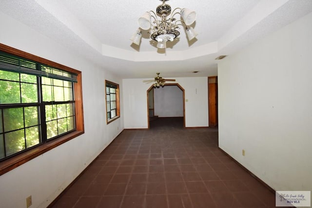 195 W 3rd St, Sebastian, TX 78594 - corridor featuring a chandelier, a tray ceiling, baseboards, and a textured ceiling