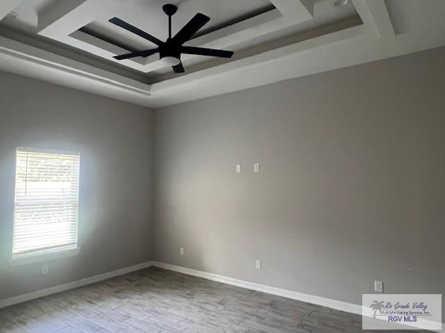 9206 Empress Ln, Harlingen, TX 78552 - spare room with a raised ceiling, wood finished floors, a ceiling fan, and baseboards