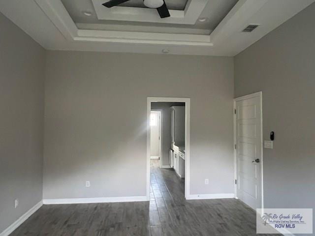 9206 Empress Ln, Harlingen, TX 78552 - unfurnished room featuring a tray ceiling, a ceiling fan, dark wood-style flooring, and baseboards