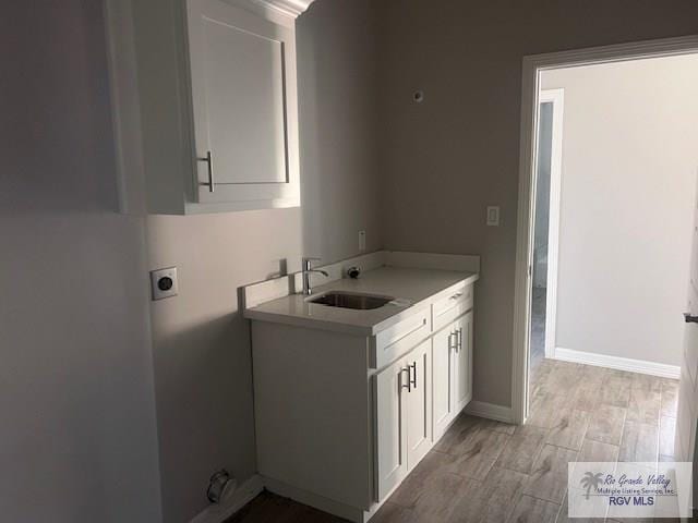 9206 Empress Ln, Harlingen, TX 78552 - laundry room with electric dryer hookup, cabinet space, light wood-type flooring, and baseboards