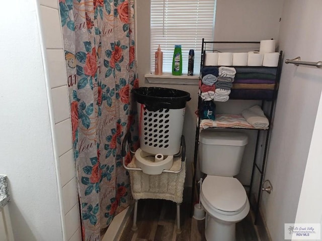 bathroom featuring hardwood / wood-style flooring, toilet, and curtained shower