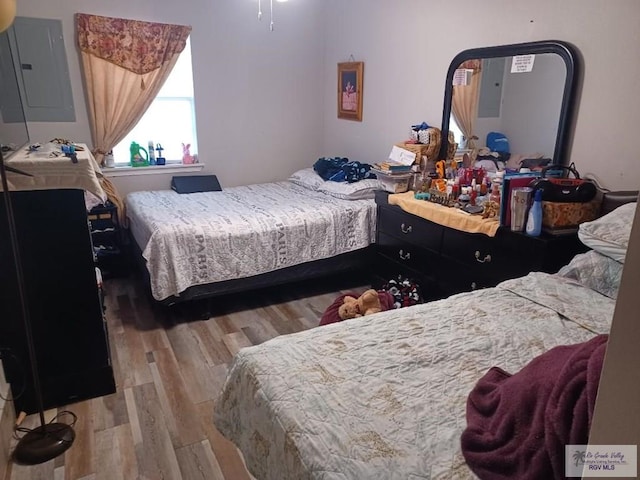 bedroom with electric panel and light hardwood / wood-style floors