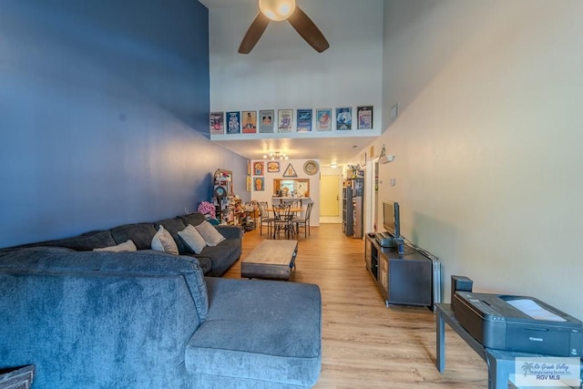 living room with ceiling fan, light hardwood / wood-style floors, and a high ceiling