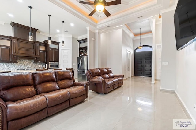 living room featuring ceiling fan, a raised ceiling, light tile patterned floors, and crown molding