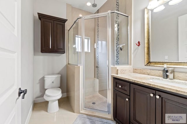 bathroom featuring tile patterned floors, vanity, a shower with shower door, and toilet