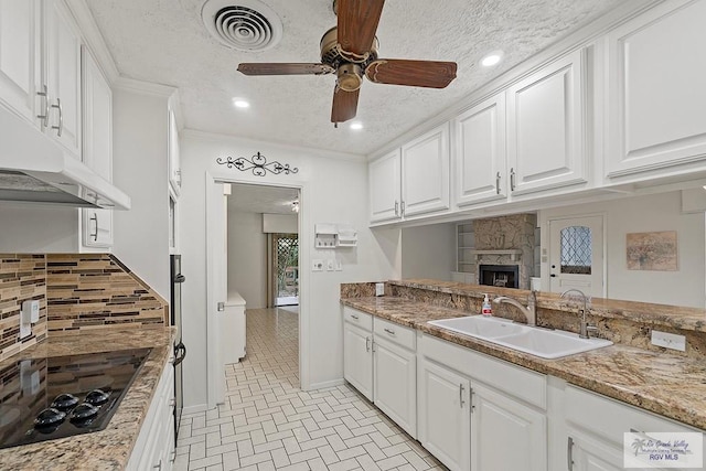 kitchen with sink, white cabinetry, a textured ceiling, and black cooktop