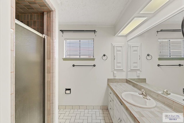 bathroom featuring tile patterned flooring, vanity, a textured ceiling, and walk in shower