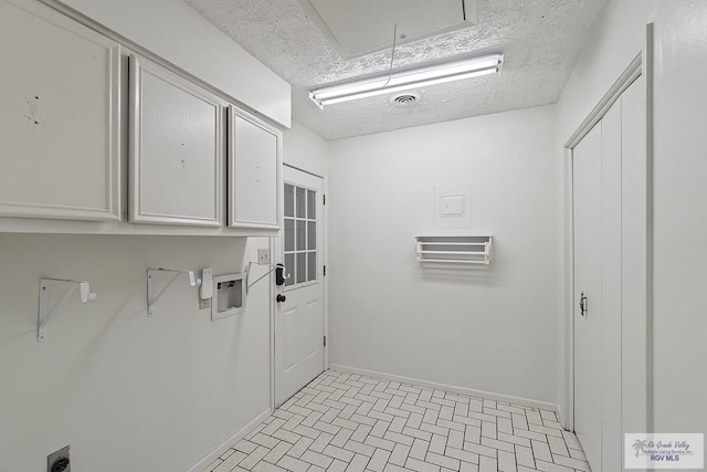 clothes washing area featuring hookup for an electric dryer, cabinets, a textured ceiling, and hookup for a washing machine