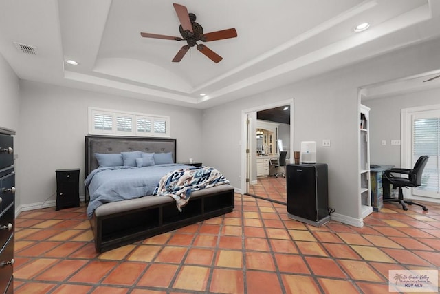 tiled bedroom featuring a tray ceiling, multiple windows, and ceiling fan