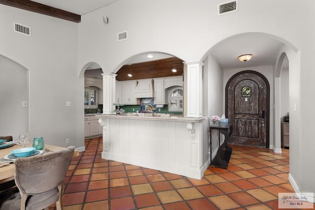 kitchen with white cabinets, backsplash, dark tile patterned floors, and beamed ceiling