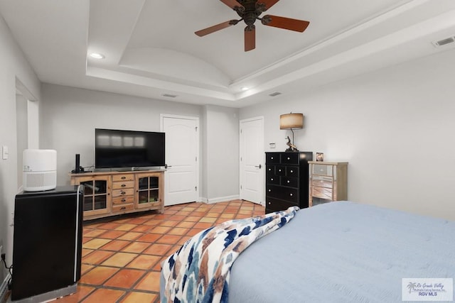 tiled bedroom with a tray ceiling and ceiling fan