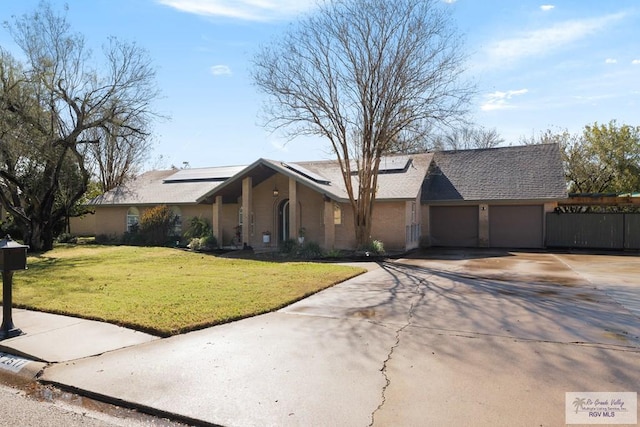 single story home featuring solar panels, a front yard, and a garage