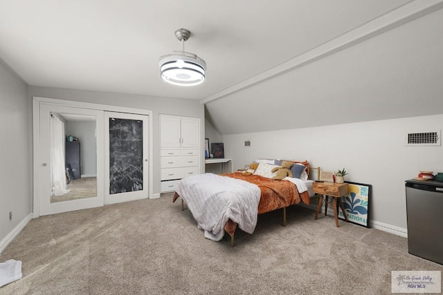 carpeted bedroom featuring stainless steel refrigerator and vaulted ceiling