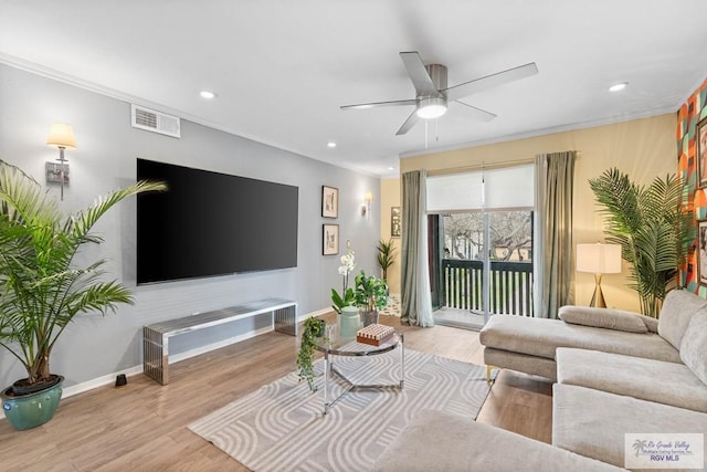 living area with visible vents, crown molding, baseboards, and wood finished floors