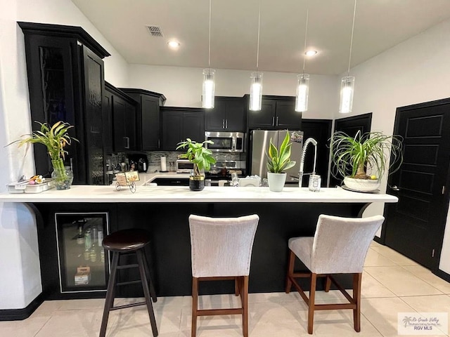 kitchen featuring backsplash, stainless steel appliances, light tile patterned floors, decorative light fixtures, and a breakfast bar area