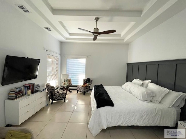 bedroom with ceiling fan, light tile patterned floors, and a tray ceiling