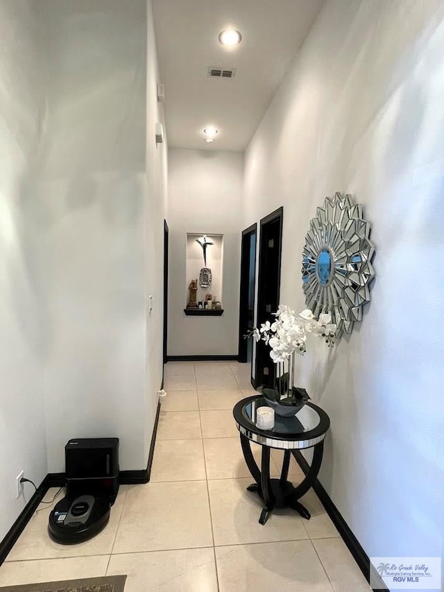 hallway featuring light tile patterned floors and a high ceiling