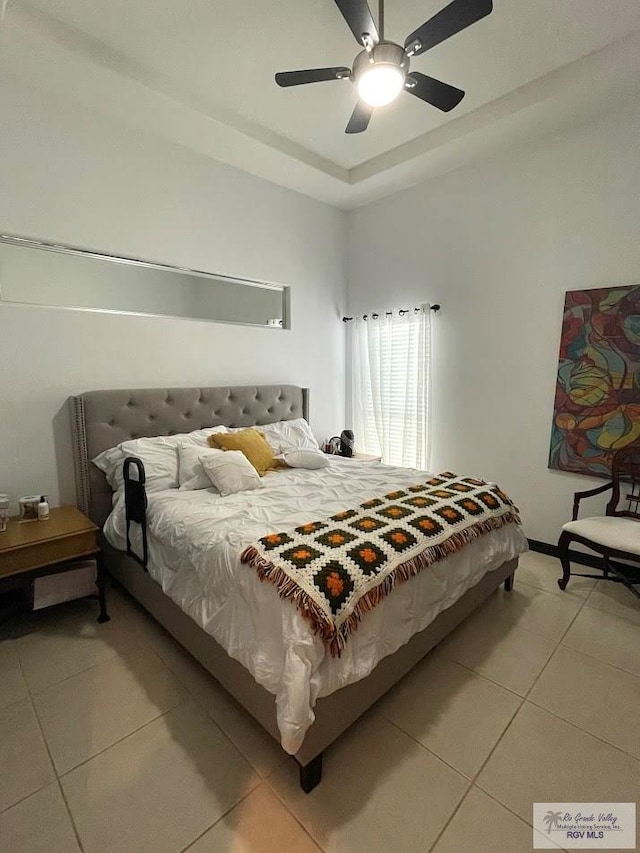 bedroom with a tray ceiling, ceiling fan, and tile patterned flooring