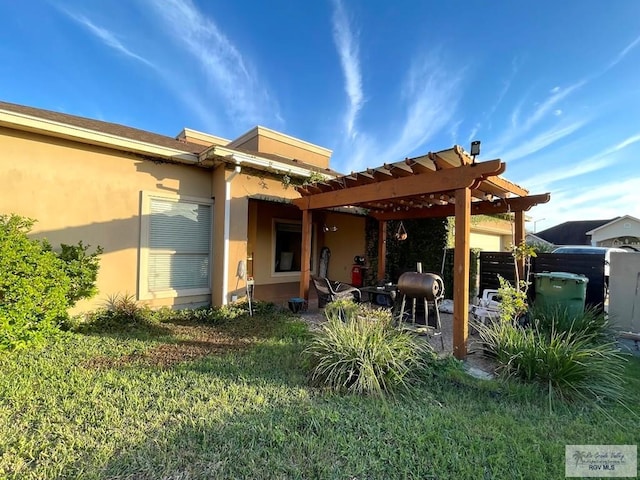 back of property with a pergola and a lawn