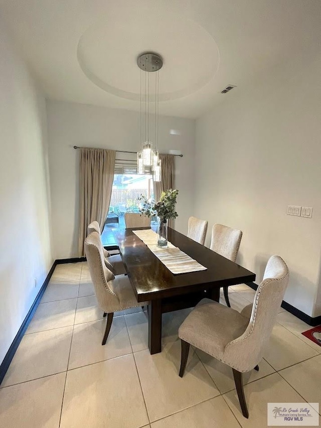 tiled dining space with a tray ceiling